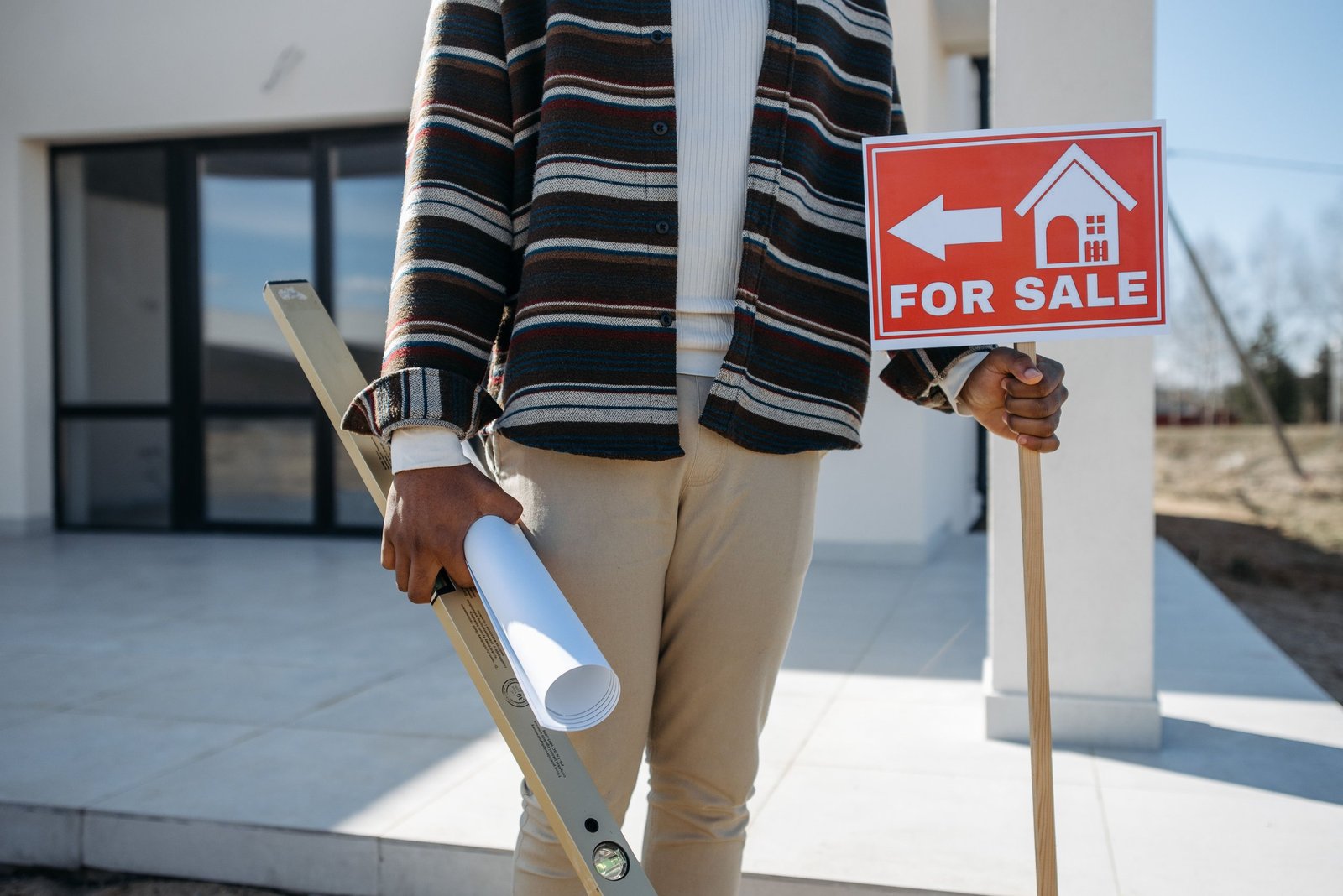 Buyer holding property plans and a house-for-sale sign